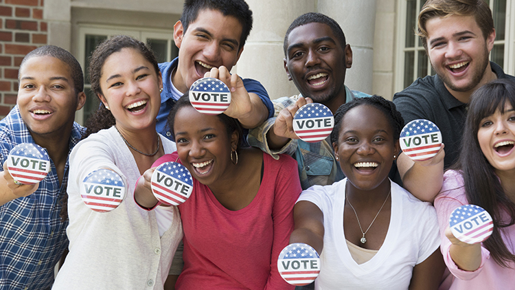 hree-quarter-length view of a group of multi-ethnic students holding buttons out at a voter registration